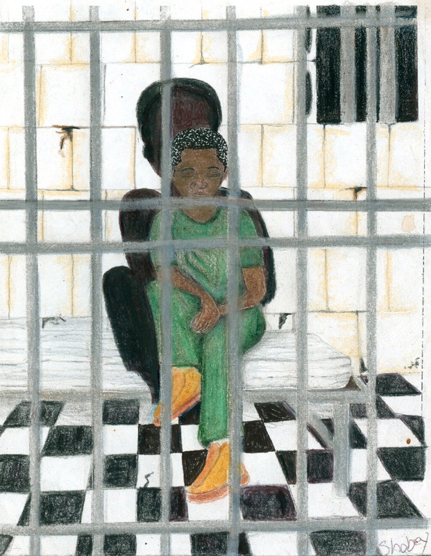 A young African American boy sits on a mattress in a jail cell. There are bars in the foreground, and a cracked cement block wall behind him. His shadow is larger than life, suggesting a full grown man's shadow.