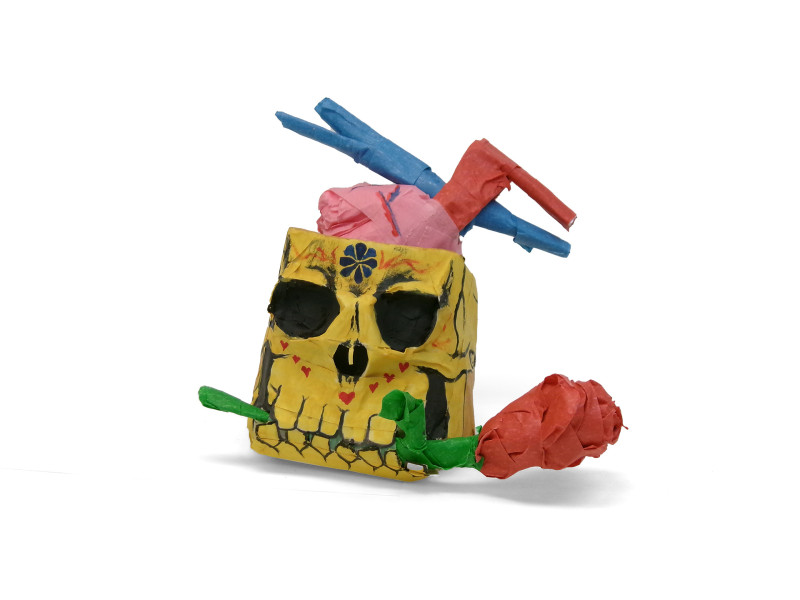 A sculpture made from masking tape, of a smiling skull with a rose in its teeth. The brain cavity is sliced open, and a heart with a blue vein and a red vein is emerging from the skull where the brain should be.